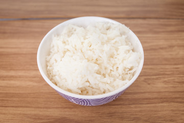 Rice cooked in a white cup placed on a wooden table, ready to serve 