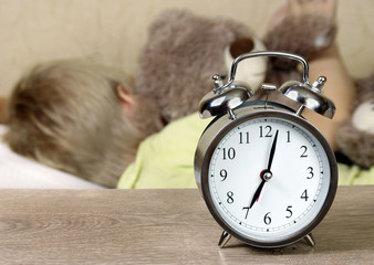 alarm clock, awakening. alarm clock and sleeping baby. morning sleep. seven in the morning.
