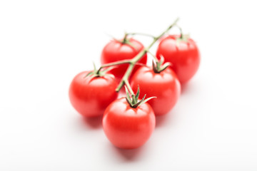 A branch of cherry tomato lies on a white surface.