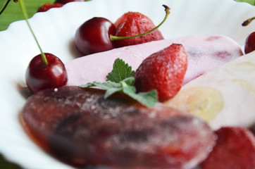 Homemade strawberry cherry banana blueberry ice cream or popsicles decorated green mint leaves on teal rustic table, frozen fruit juice, vintage style, top view