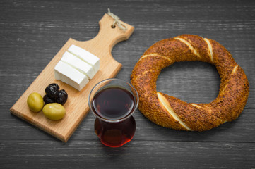 Turkish breakfast on black wooden table, black tea, bagels, olives, cheese.