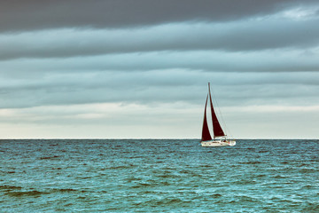 Boat with black sails on the sea in stormy weather