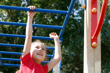 Fototapeta premium A girl climbs the stairs on the playground in the park