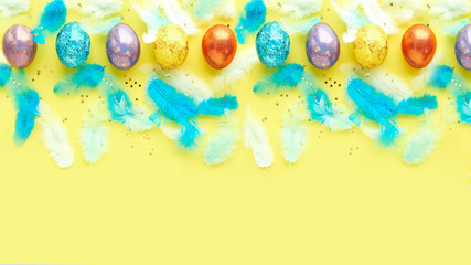 square of easter eggs on a yellow background. scattered blue feathers. banner for text
