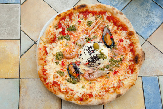 Delicious seafood pizza with prawns and mussels on colorful table in Ljubljana cafe, Slovenia