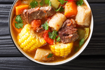 Latin American Sancocho thick meat soup with vegetables close-up on a plate on the table. horizontal top view