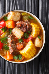 Latin American Sancocho thick meat soup with vegetables close-up on a plate on the table. Vertical...