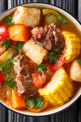 Sancocho Recipe a hearty and absolutely delicious stew made with meat, vegetables and spice close-up on a plate. Vertical top view