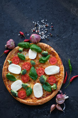 Italian pizza with Mozzarella cheese, tomatoes, broccoli, Spices and fresh basil. Pizza on black stone background