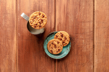 Chocolate chip cookies, shot from the top on a dark rustic wooden background with milk and a place for text