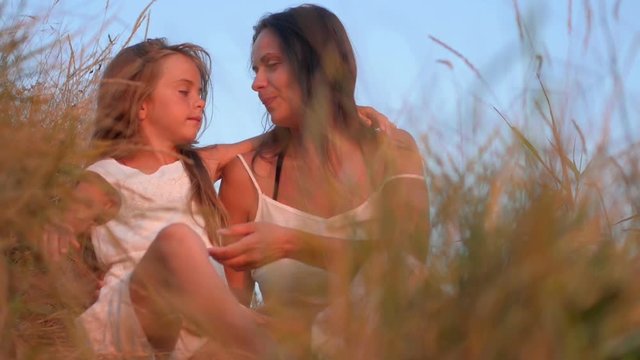 mother and little daughter are relaxing in the evening field, family in nature