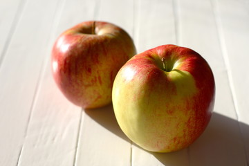 Two jonagold apples in the sun on a white table