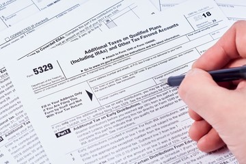 Obraz premium Tax reporting. Human fills out the 5329 tax form on background other forms