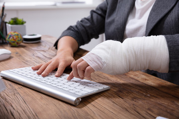Businesswoman With Bandage Hand Using Keyboard