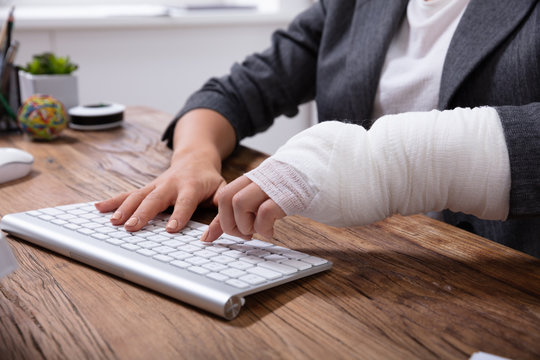 Businesswoman With Bandage Hand Using Keyboard