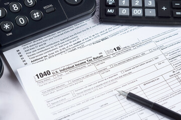 Tax reporting. 1040 tax form, pen, phone and calculator on light background