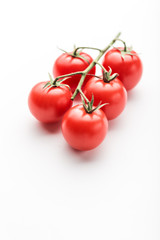 A branch of cherry tomato lies on a white surface.