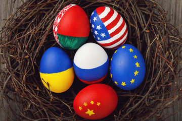 Fototapeta na wymiar Easter eggs painted in colors of the flags of different states of the world in the nest, top view