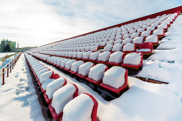 Sports stadium bleachers in winter. Empty seats of grandstands covered by snow - Powered by Adobe