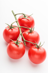 A branch of cherry tomato lies on a white surface.