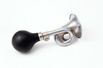 A worn iron horn or klaxon from a vintage car or bicycle lies horizontally. Isolated on a light background with a shadow.  The horn is turned right