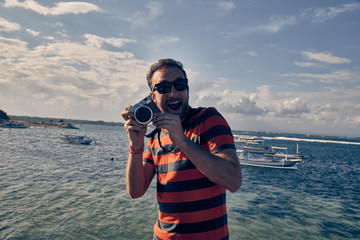 Obraz premium Man using vintage film camera on a ocean / sea vacation.