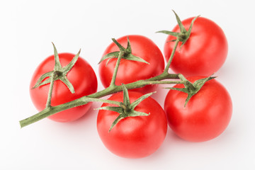 A branch of cherry tomato lies on a white surface.