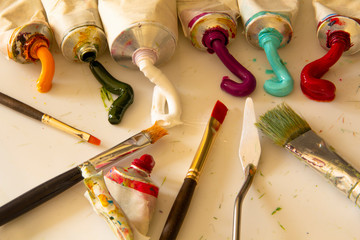 Tubes with extruded oil paints, artistic brushes, palette knife on palette. The process of creating...