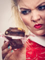 Fotobehang Skeptical woman holding chocolate cupcake © Voyagerix