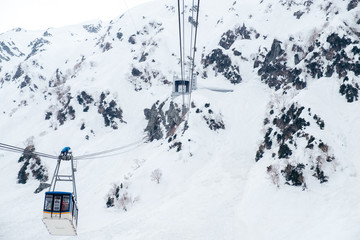 Ropeway Tateyama Kurobe Alpine Snow Wall Walk, repairman or maintenance man on top of airline cable rope way, so dangerous working while transport passengers to the peak point of Japan's mountain.
