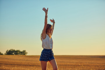 Cute young woman jumping in a wheat field.