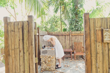 Portrait of beautiful young woman washing her face splashing water in outdoor bathroom