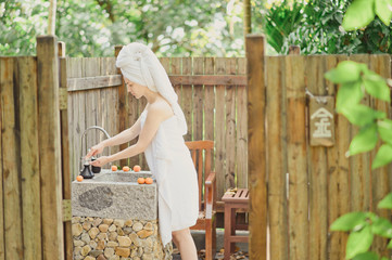 Portrait of beautiful young woman washing her face splashing water in outdoor bathroom