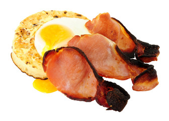 Fried egg and smoked bacon rashers on a large English crumpet isolated on a white background