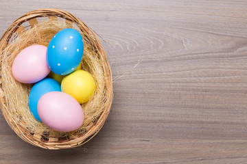 Easter eggs in the basket on wooden background
