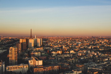 Eiffel tower between buildings in the last rays of the sun. Aerial view of Paris, France
