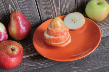 A pear is cut mugs on an orange dish.