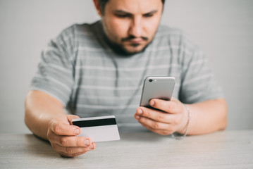 Cropped picture of man with credit card white pattern and phone