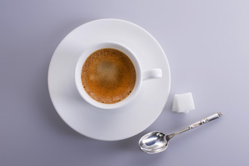 Cup of expresso coffee seen from above with sugar lumps and a silver spoon.