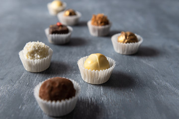 Assortment of fine chocolate candies, white, dark and milk chocolate on grey background. Sweets background, side view, close up