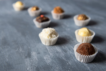 Assortment of fine chocolate candies, white, dark and milk chocolate on grey background. Sweets background, side view, close up