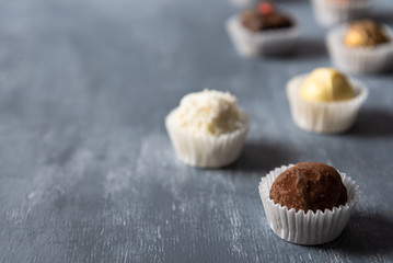 Fine chocolate candies, white, dark and milk chocolate on grey background. Sweets background, side view, close up, copy space