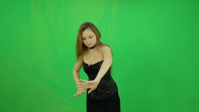 Young witch makes poison by magic waves at green screen