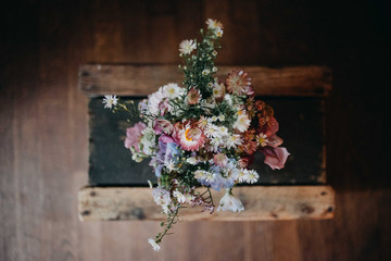 Fototapeta na wymiar Ein Blumenstrauss auf einem Holztisch von oben fotografiert. Die Farbe der Blumenvase ist grün, weiß und sommerlich.
