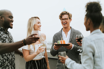 Cheerful friends celebrating at a rooftop birthday party