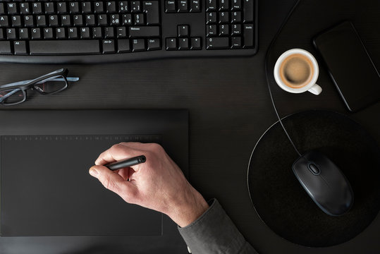 Designer drawing on graphic tablet on black desk