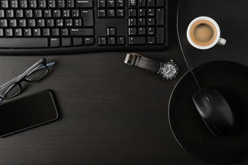 Total black desk with cup of coffee, pc and personal items