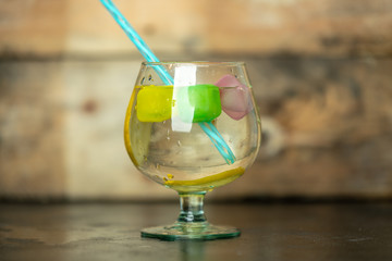 Refreshing, cold drink in a glass with colorful ice cubes and slices of citrus fruit