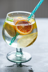 Refreshing, cold drink in a glass with colorful ice cubes and slices of citrus fruit