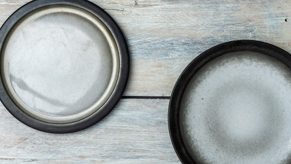 top view on white, wooden table top with two empty gray and white plates